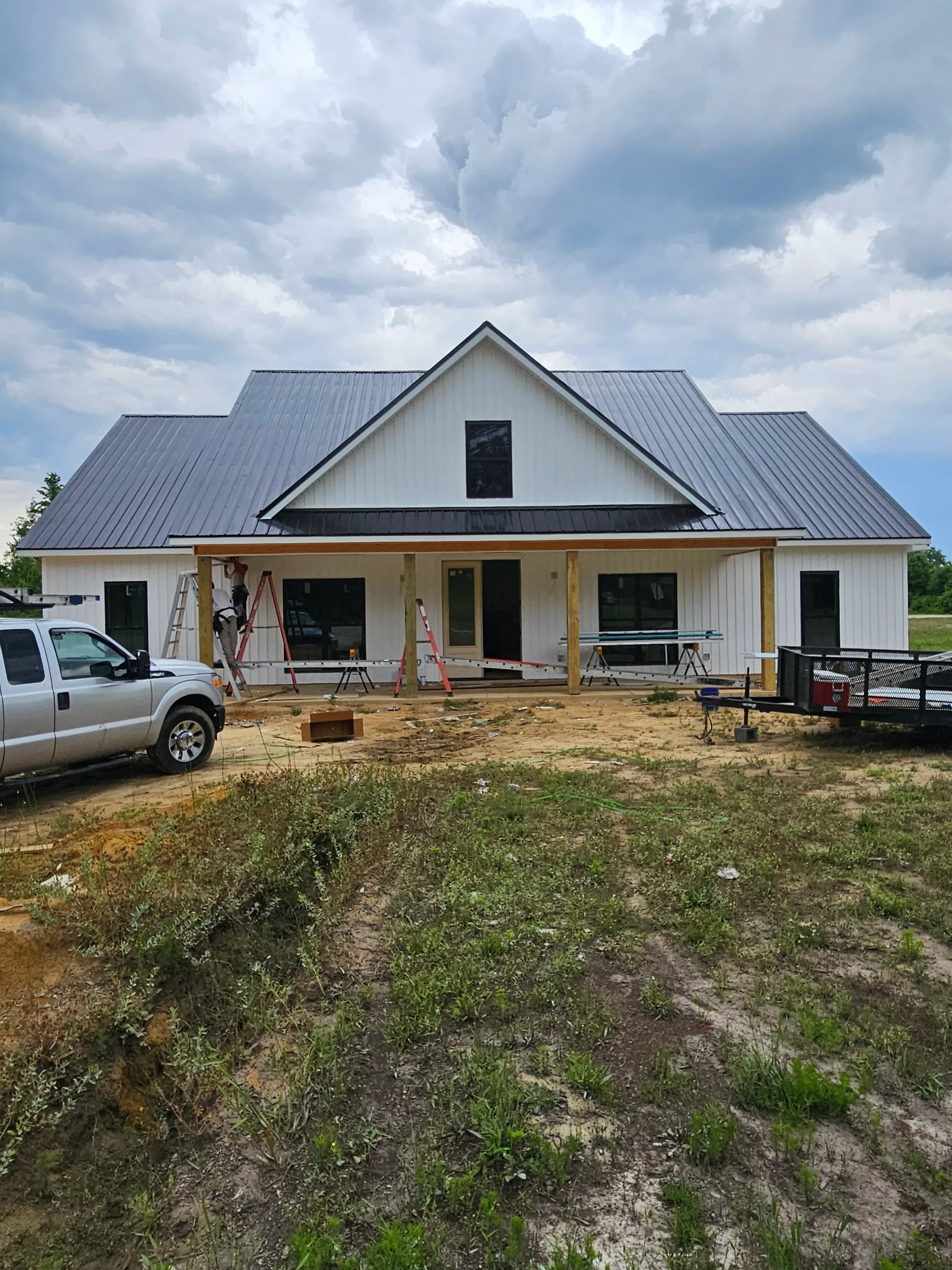 Gray standing seam metal roof installation on multi-plane residential home with proper flashing
