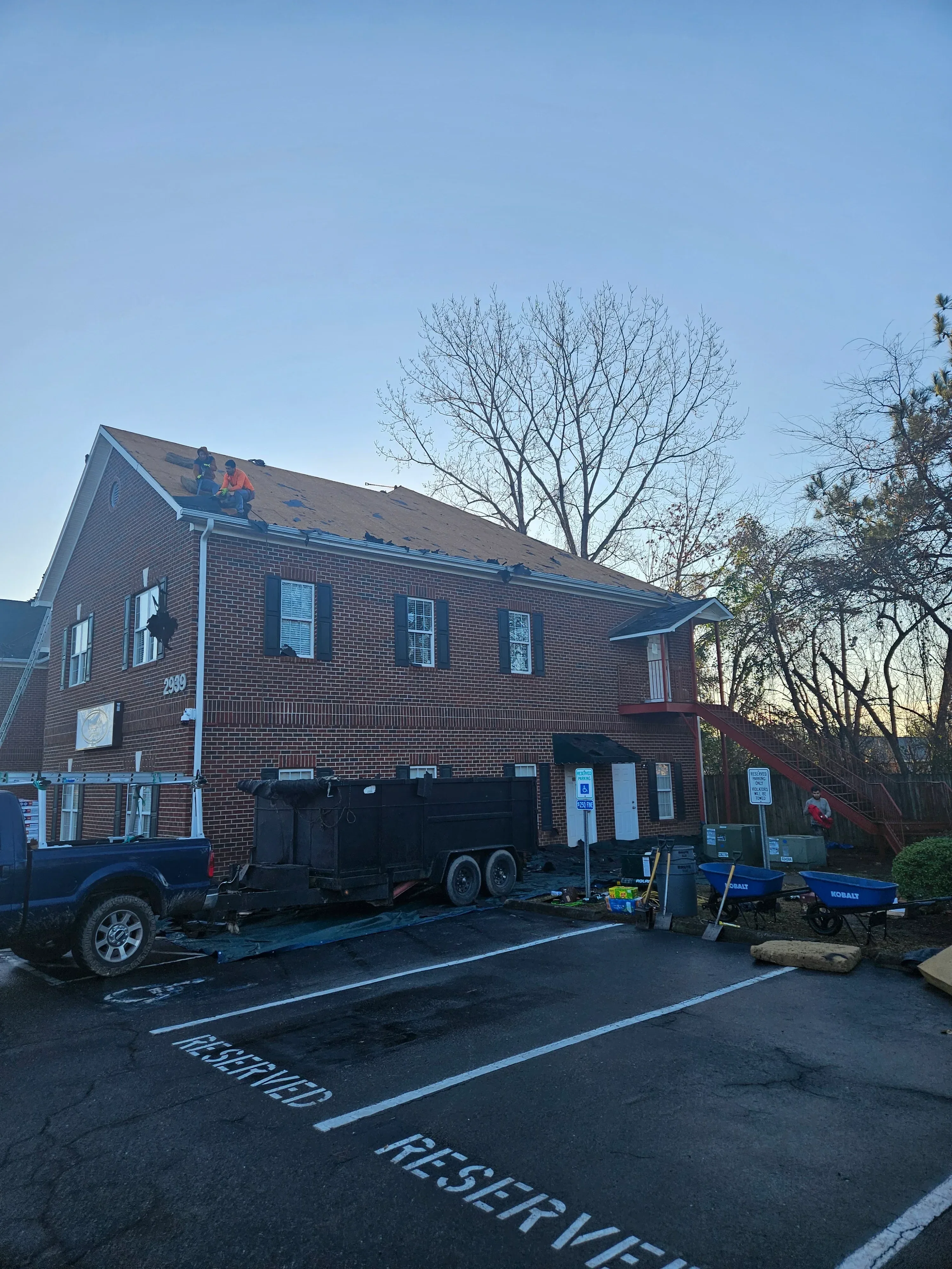 New architectural shingle roof installed on brick commercial building with multiple skylights and roof penetrations