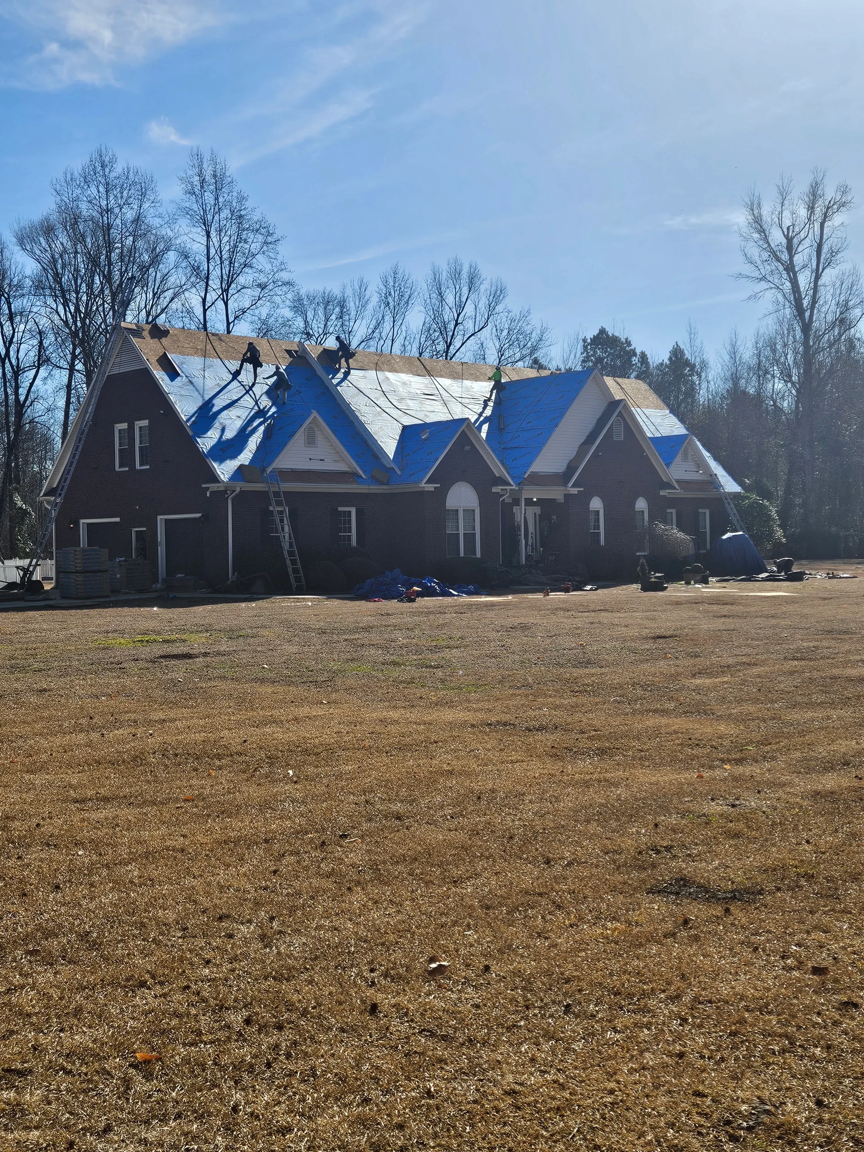 Multi-story building with dark asphalt roof and blue metal siding panels installed