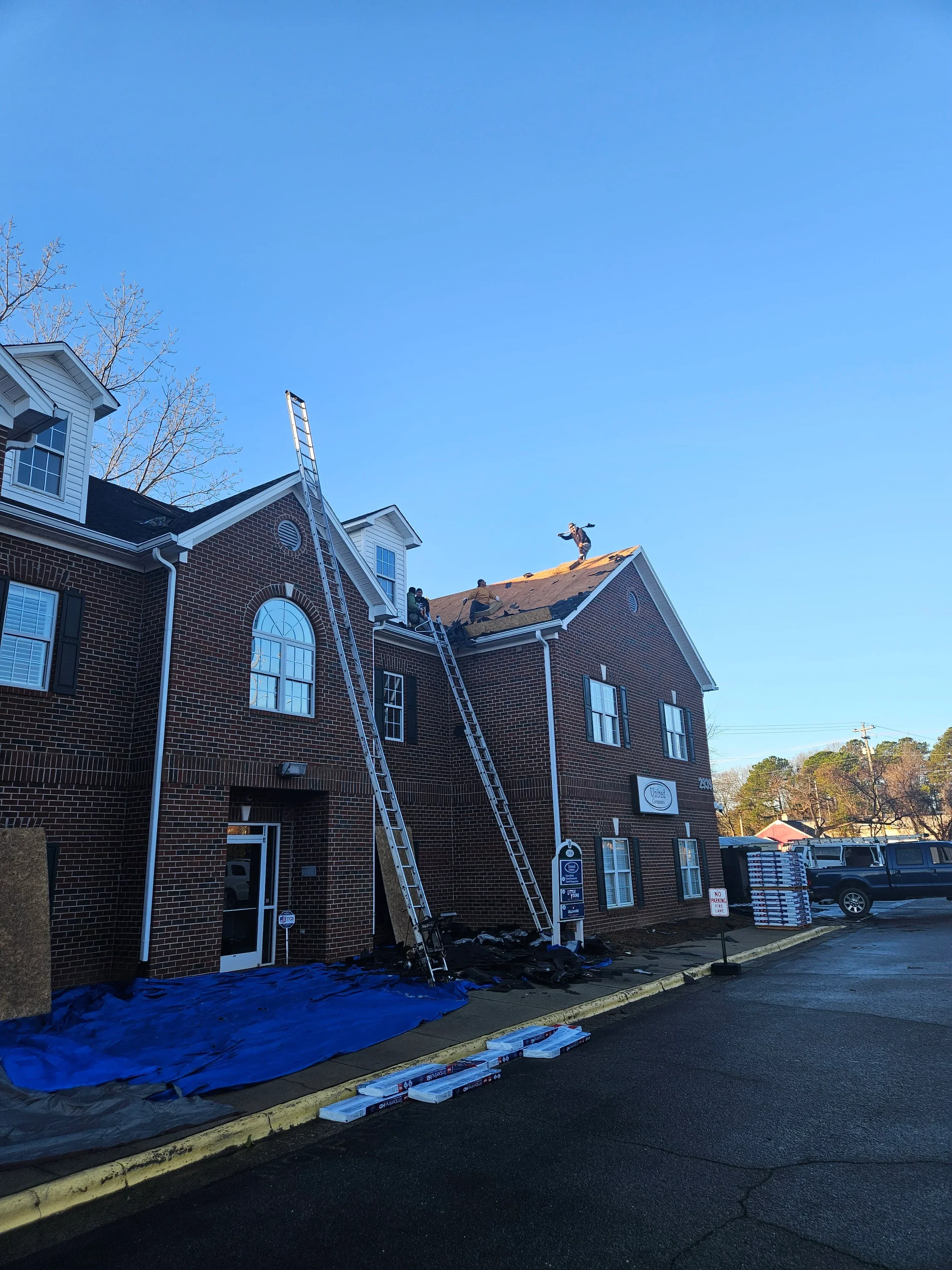 Dark asphalt shingle roof with metal flashing and gutters on multi-story brick building