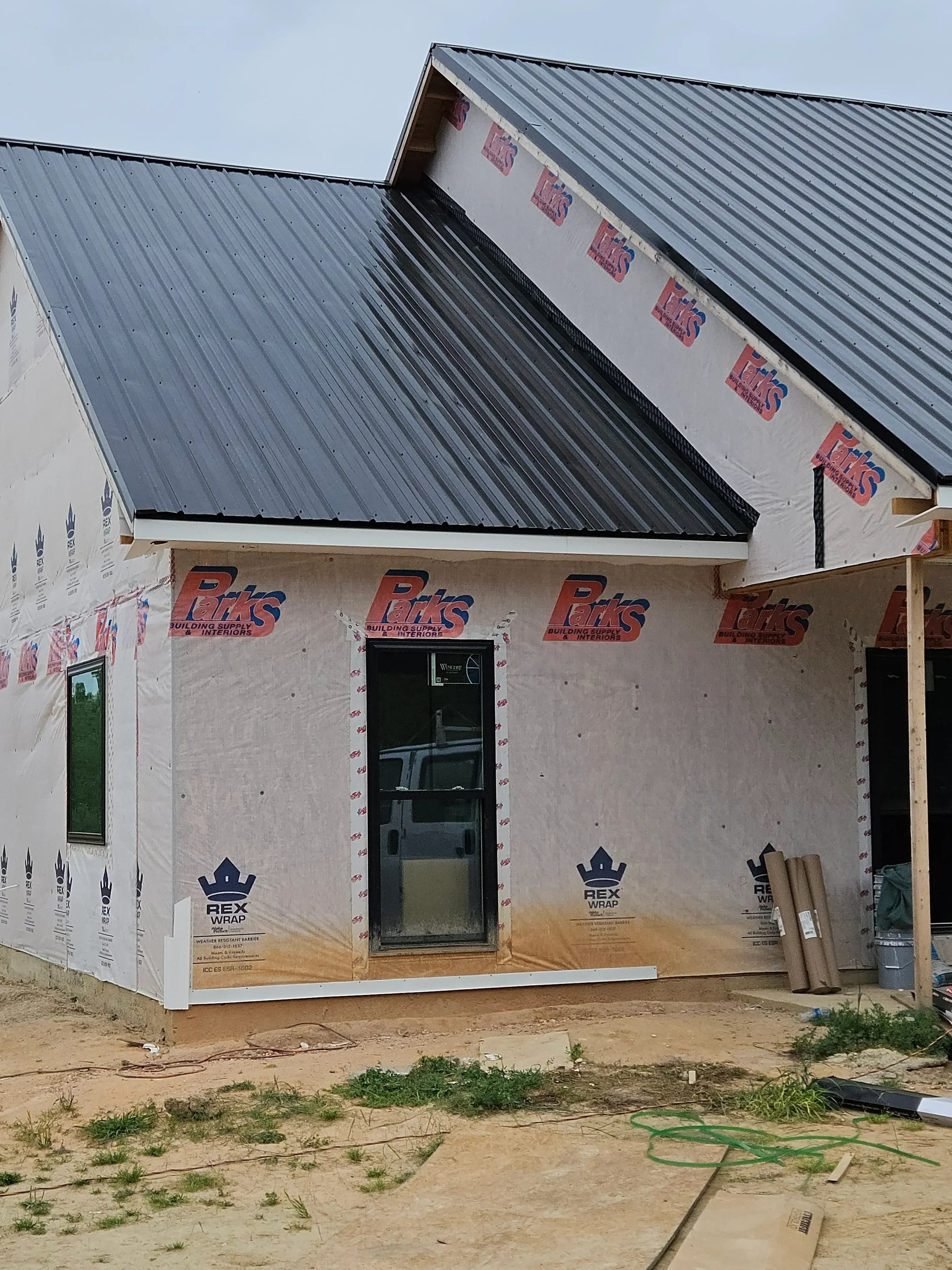 Metal corrugated roof panels installed with white underlayment, soffit, and fascia components during construction