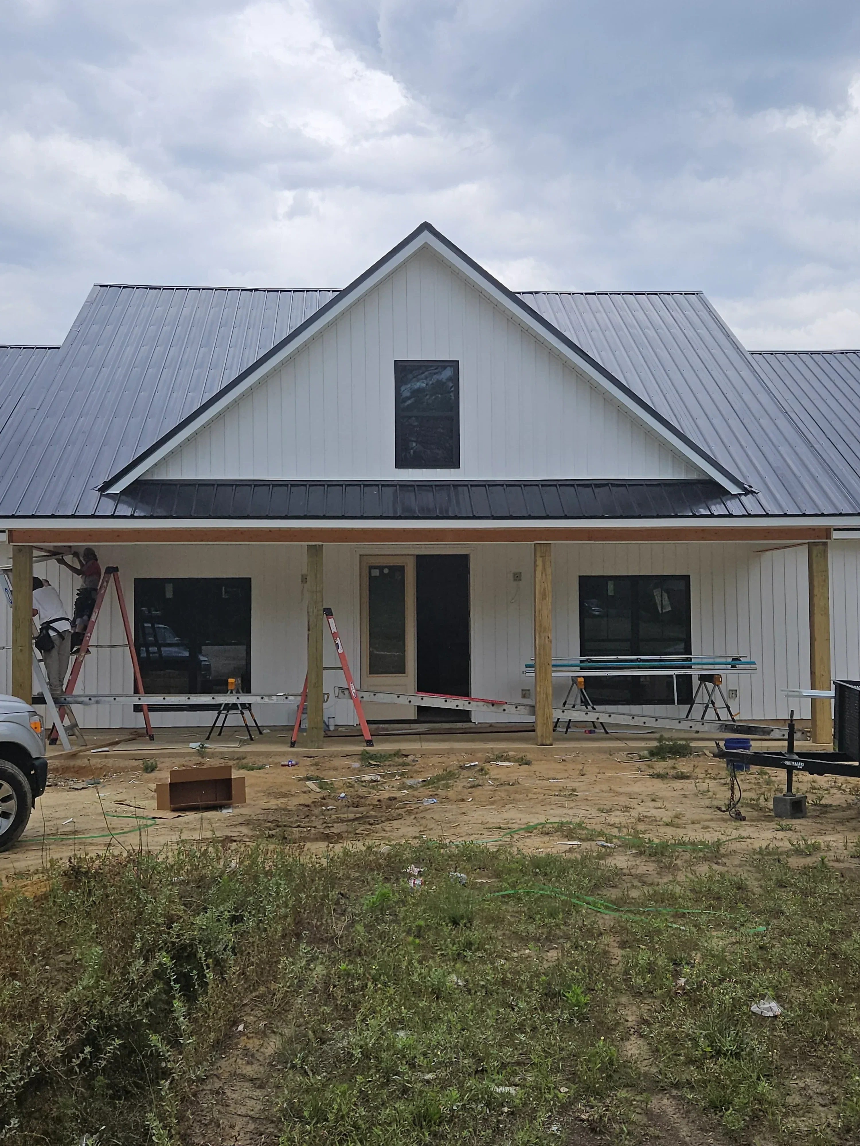 Metal standing seam roof installation with gray panels and professional flashing details