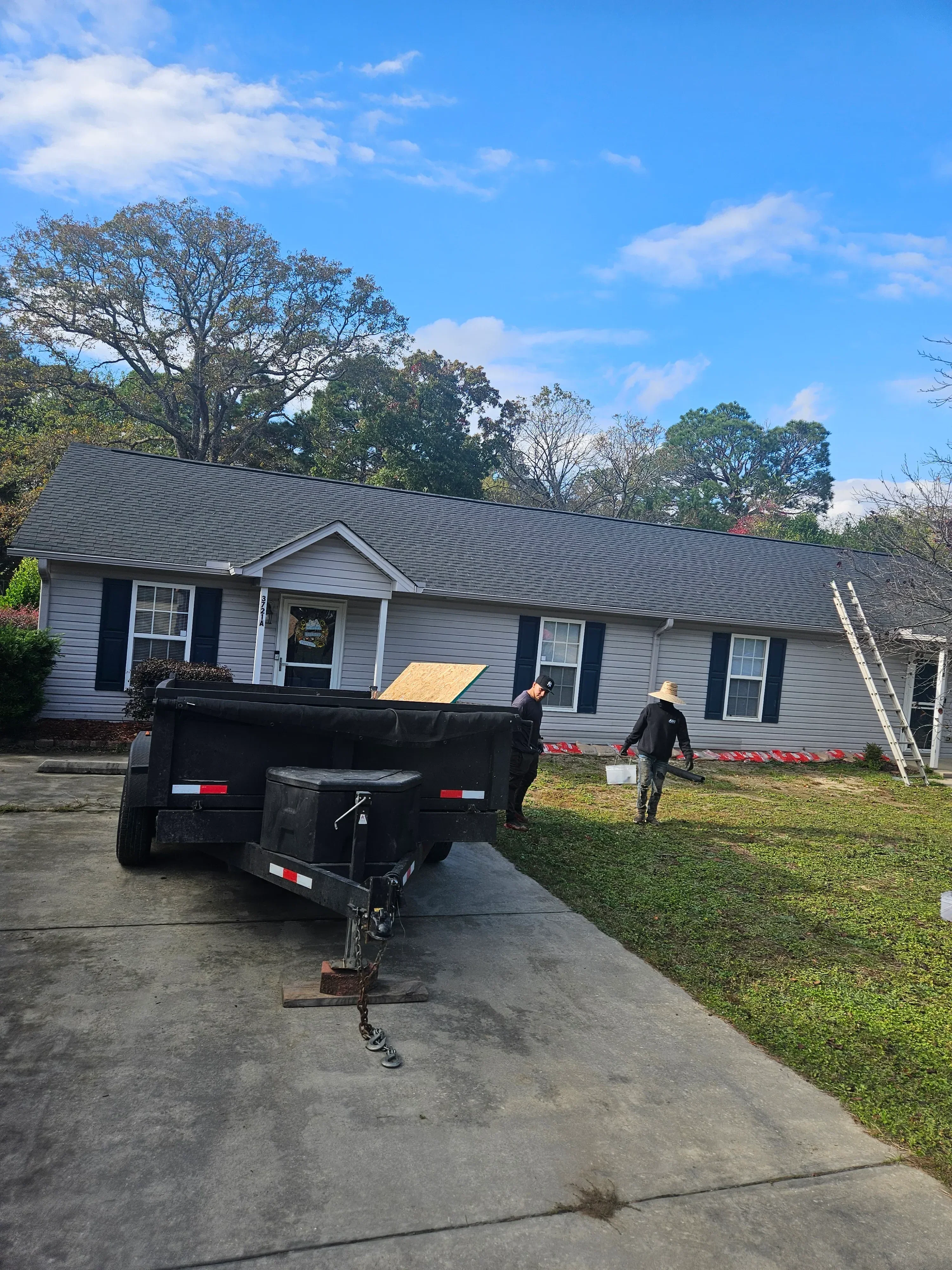 Charcoal gray corrugated metal roof installation with multiple sections and integrated windows